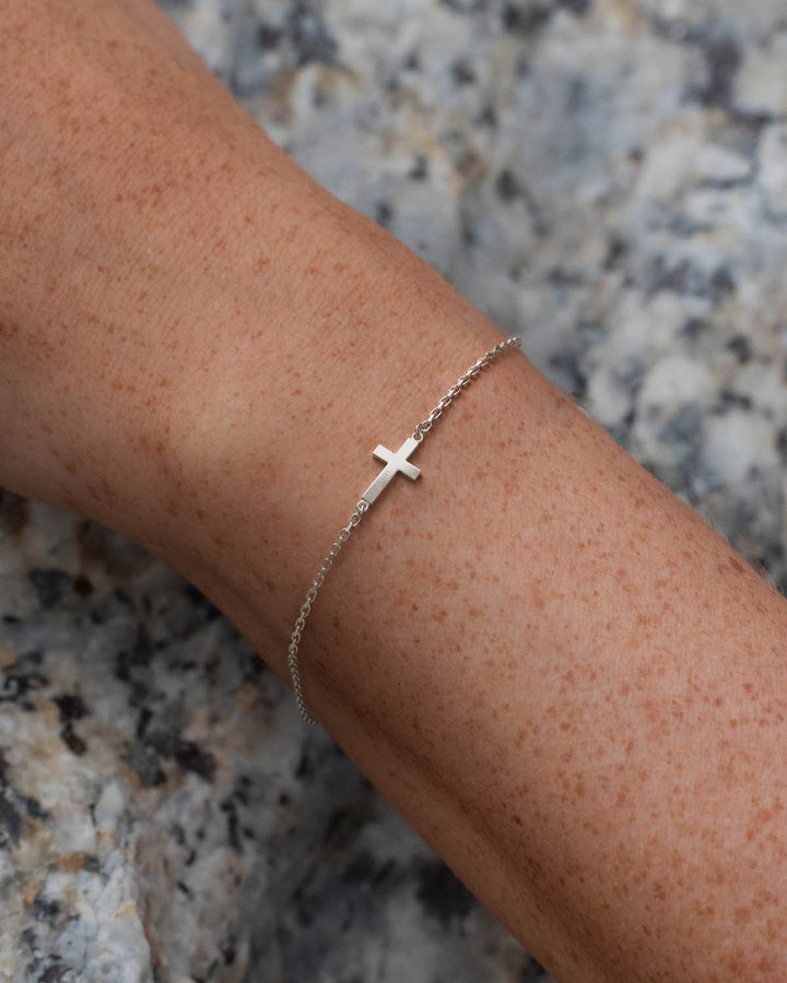 Silver side cross bracelet worn on a woman's wrist
