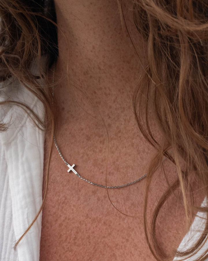 Silver side cross necklace worn by a woman