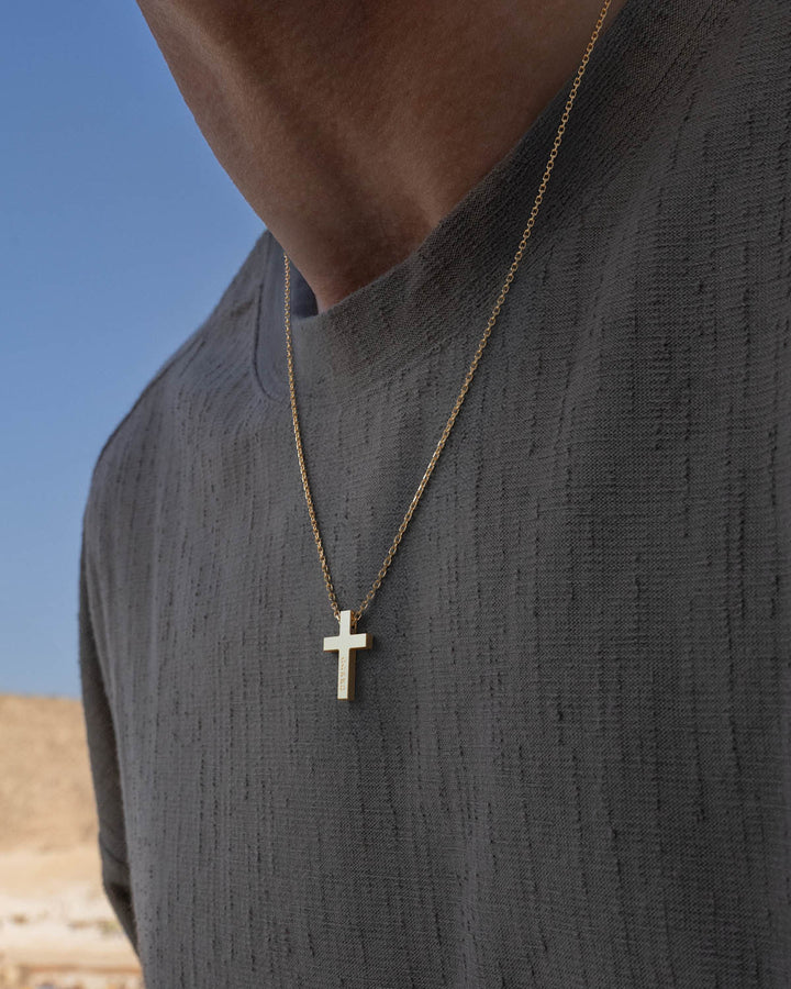Gold cross necklace worn by a man in a grey t-shirt
