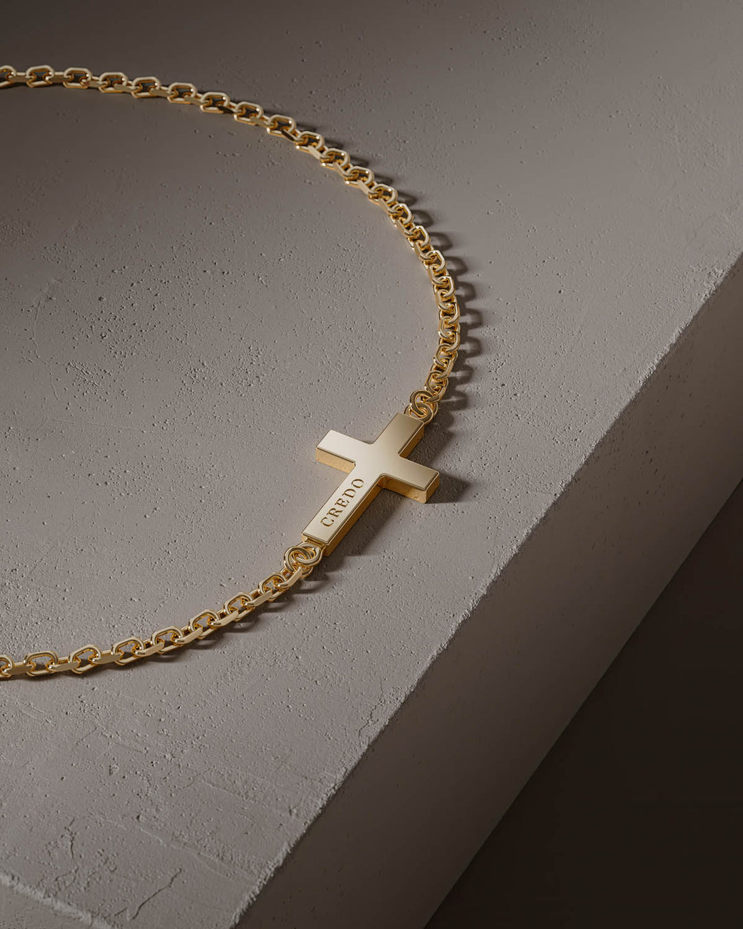 Side cross bracelet in gold, close-up of the cross on a stone block
