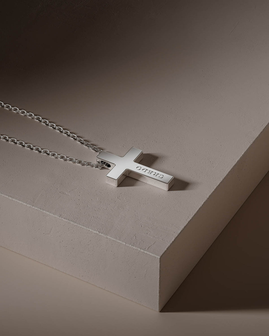 Cross necklace in silver on a stone block