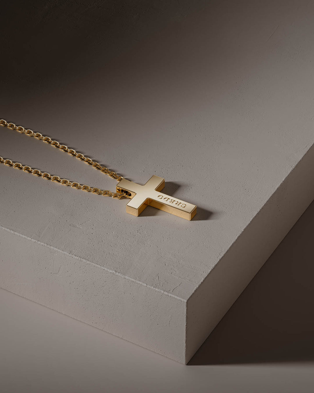 Cross necklace in gold on a stone block