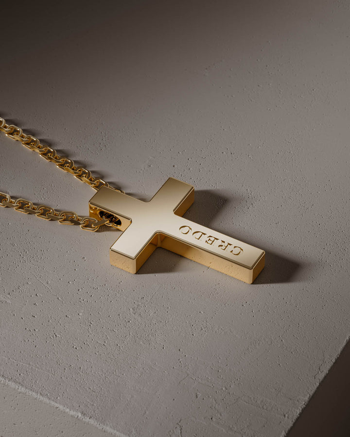 Gold cross pendant with CREDO engraving, close-up