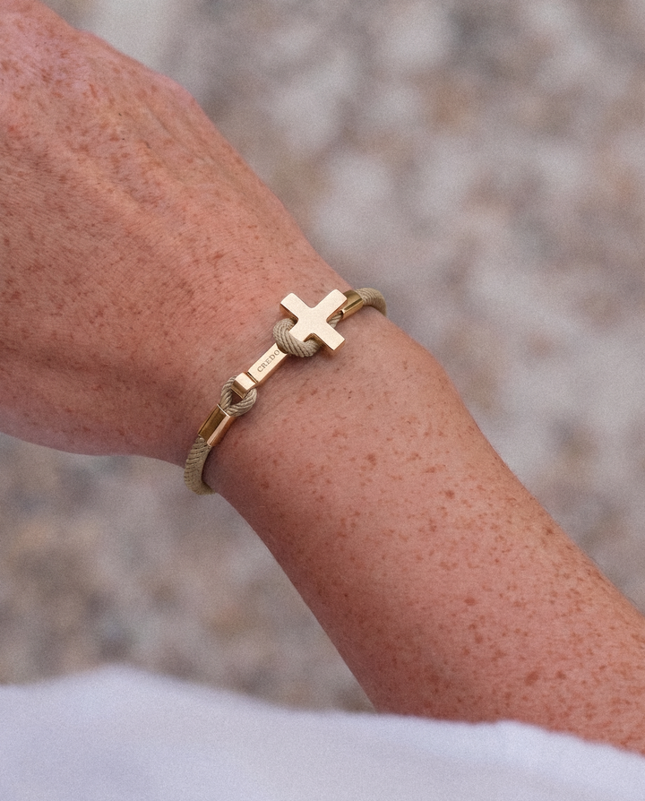 Women's Rope Cross Bracelet in khaki with a gold cross, lifestyle view