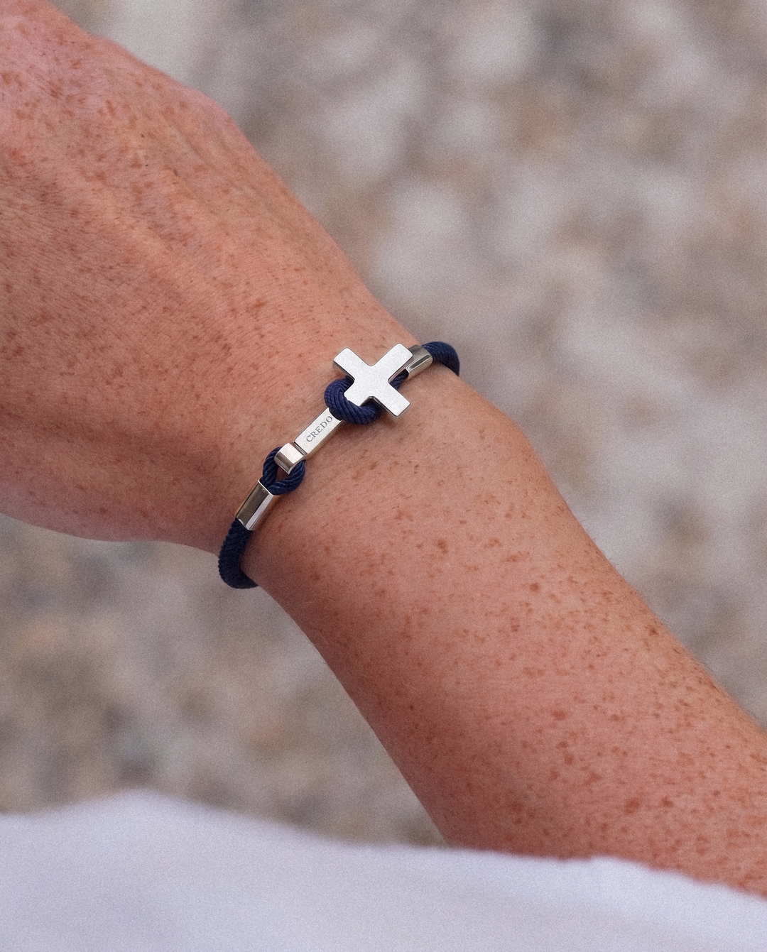 Women's Rope Cross Bracelet in navy blue with a silver cross, lifestyle view