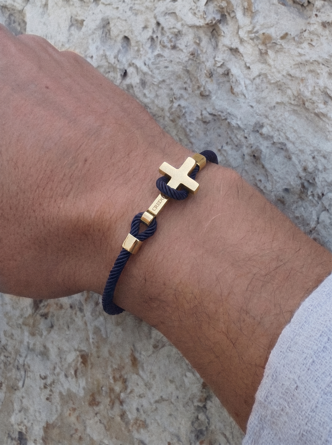 Men's Rope Cross Bracelet in navy blue with a gold cross, lifestyle view