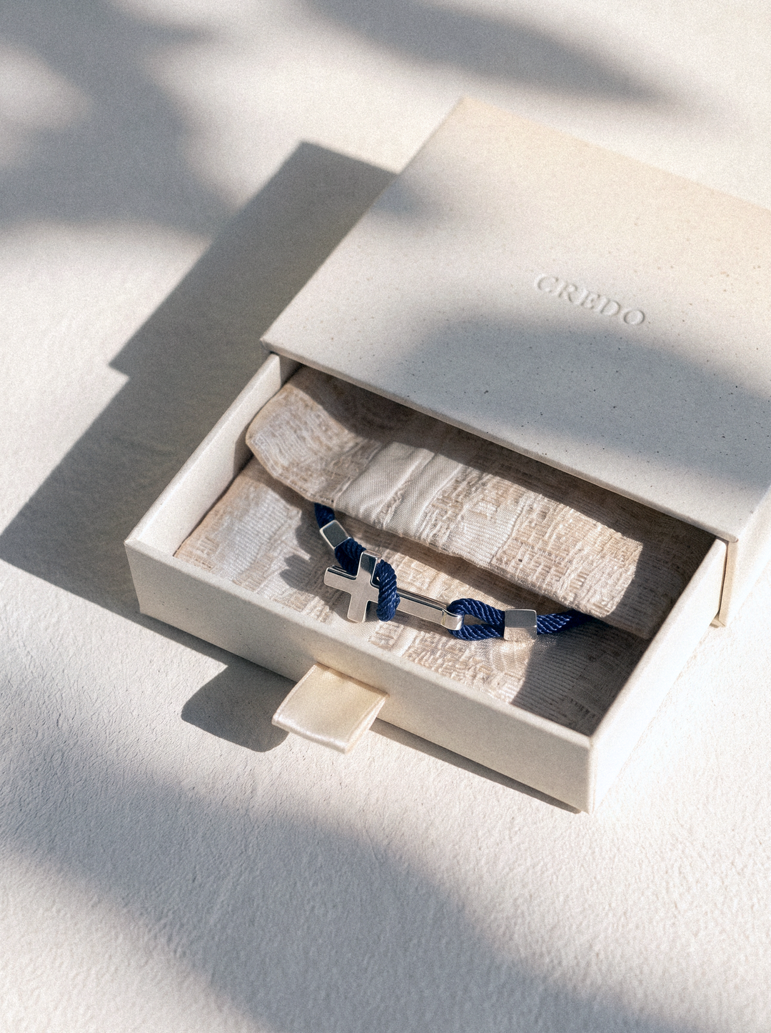 Credo gift box with a woven pouch and a rope cross bracelet inside