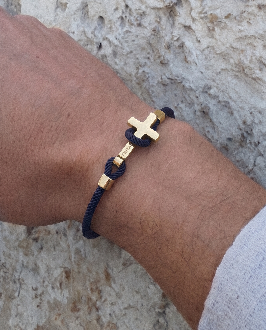 Men's Rope Cross Bracelet in navy blue with a gold cross, lifestyle view